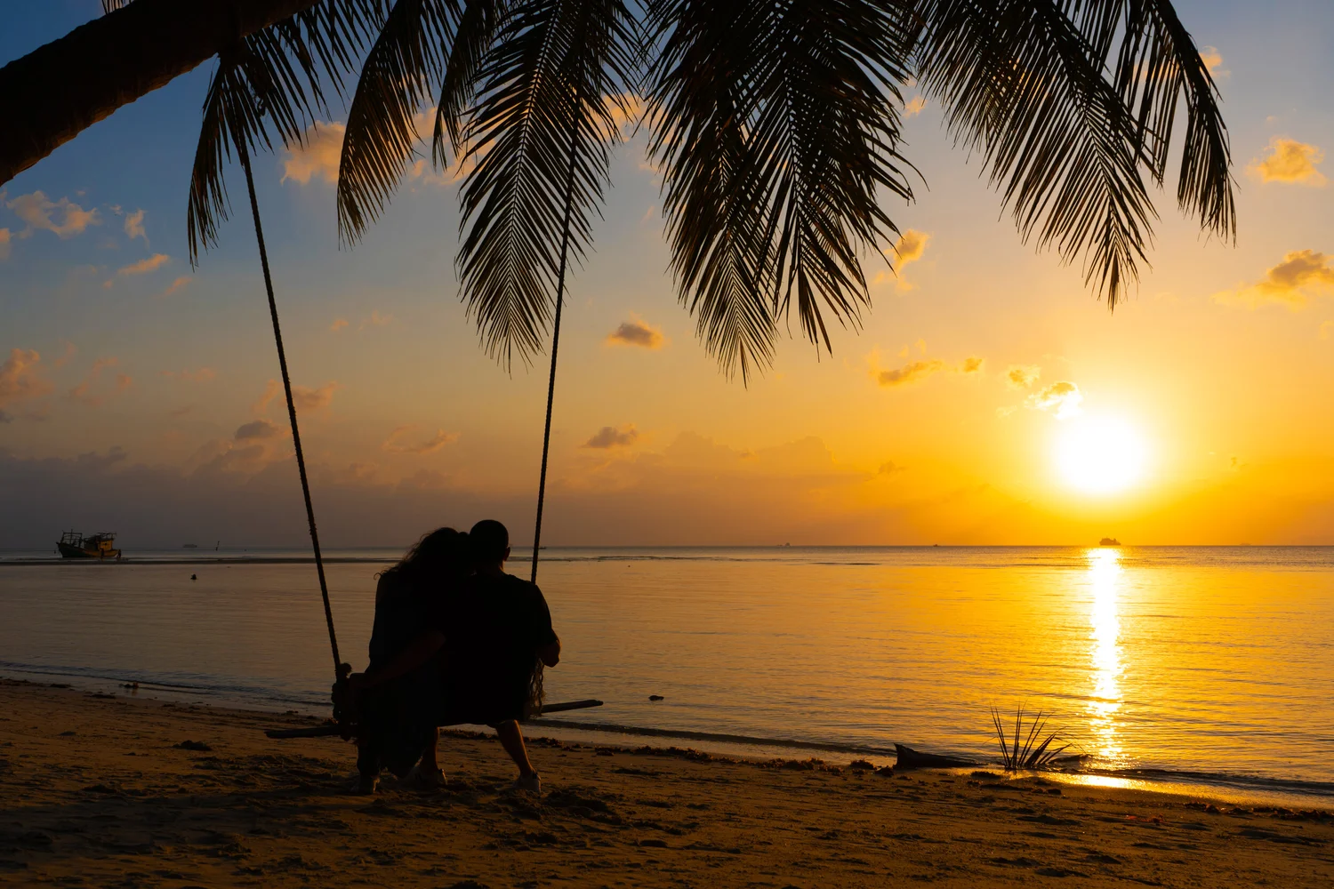 Couple walking through a field at sunset