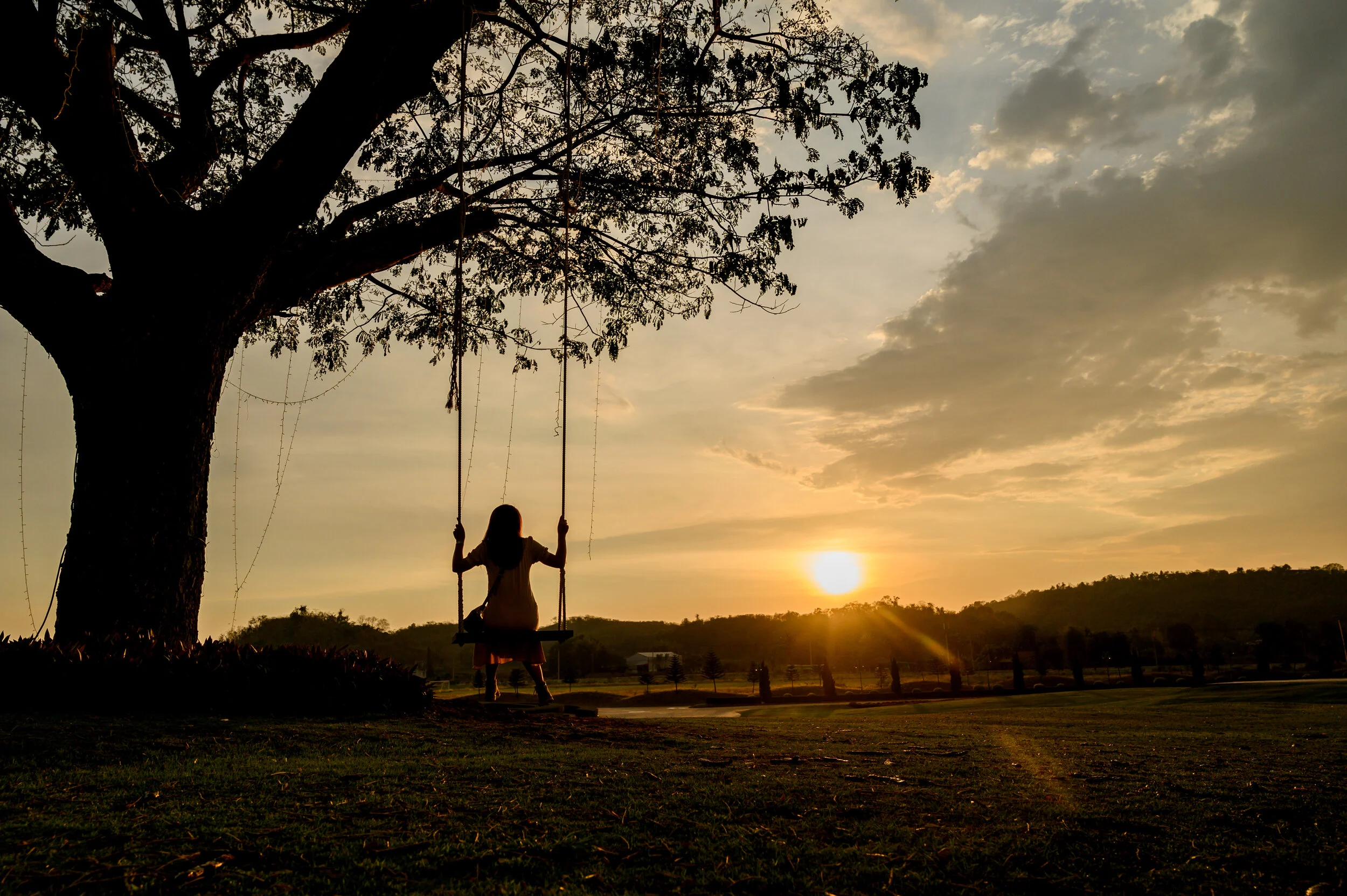 Person sitting on a swing at sunset